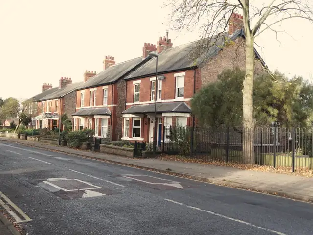 Row of red-brick terraced houses with slate roofs and tall chimneys on Station Road, Haxby