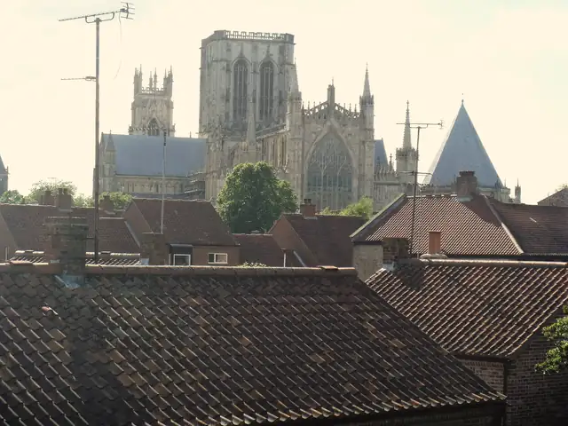 Weathered red clay pantile roofs and brick chimneys in York with York Minster rising behind