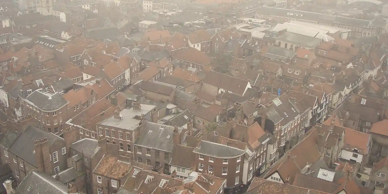 Misty view over York city-centre streets and roofs of red pantiles and grey slate, seen from York Minster
